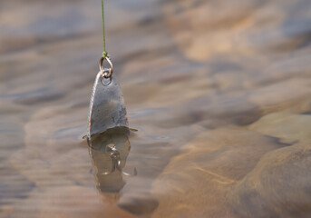 spinner, metal bait in clear water, fishing tool.