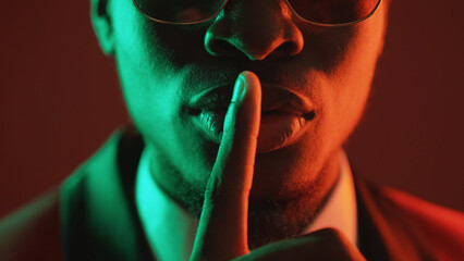 Shush gesture. Man secret. Confidential conspiracy. Green red neon light unrecognizable gentleman...