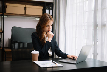 Young attractive Asian woman smiling thinking planning writing in notebook, tablet and laptop working from home at office .