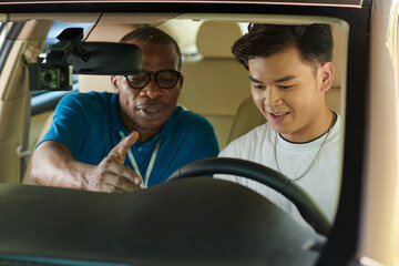 Driving school instructor showing speedometer and odometer on car dashboard to student