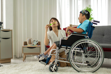 Portrait of enjoy happy love family asian mother playing and carer helping look at disabled son child sitting in wheelchair moments good time at home.disability care concept