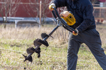 Worker digs the ground with a gasoline blower in the garden