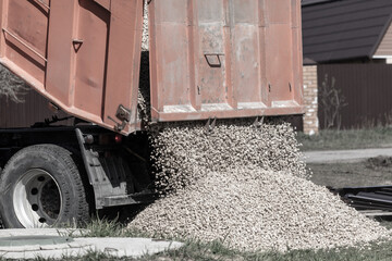 Truck pours rubble on the ground.