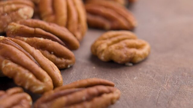 Dry natural pecans on a board. The hand takes a tasty nut. Diet healthy food