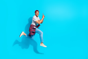 Fototapeta na wymiar Full body profile photo of excited handsome guy jumping rush empty space use smart phone isolated on blue color background