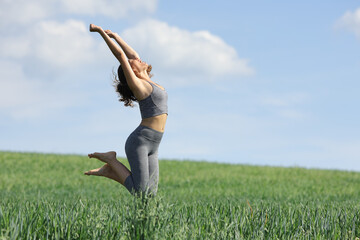 Sportswoman jumping happy in a green field
