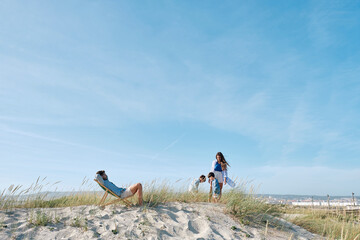 Father relaxing on chair with family spending leisure time at beach