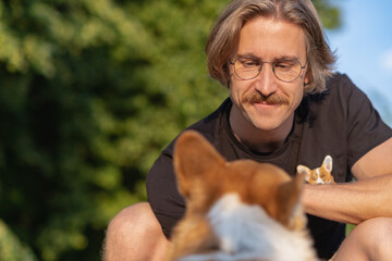 portrait of a Young man sitting opposit his dog breed corgi dog