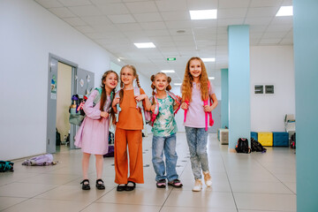 Smiling school students standing together in school corridor
