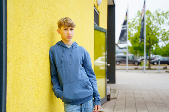 Thoughtful boy leaning on yellow wall