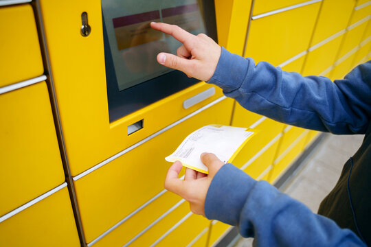 Boy with ticket entering details on parcel locker screen