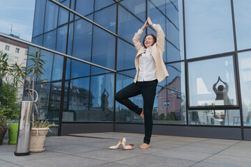 Businesswoman practicing tree pose outside office building