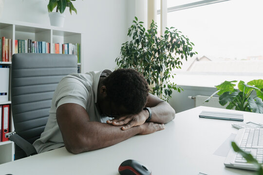 Businessman resting with face down on desk in office