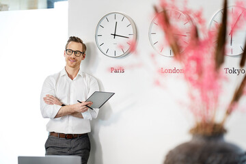 Happy businessman leaning with tablet PC on wall