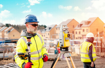 Surveyor builder site engineer with theodolite total station at construction site outdoors during...