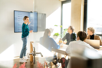 Businesswoman pointing on interactive whiteboard and giving presentation in office