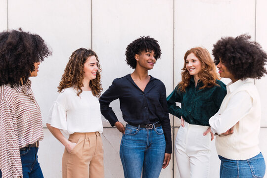 Smiling businesswomen together spending time in front of wall