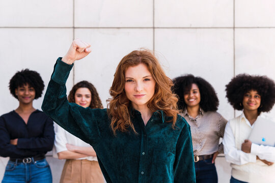 Confident businesswoman with colleagues standing in background