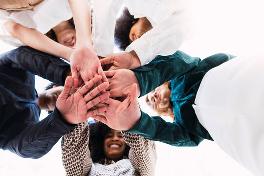 Happy businesswomen stacking hands and huddling together in unity