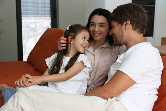 Smiling woman with family sitting on sofa at home