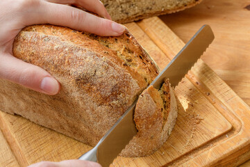 Bochenek chleba krojony nożem na drewnianej desce w kuchni - obrazy, fototapety, plakaty
