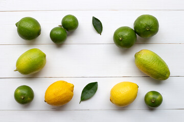 Ripe lemons and limes on white wooden.
