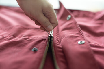 Closeup woman hand open zipper of red jacket. Textile, fashion, clothing concept. Secret Keeper, Truth Revealing, Adhesion, Adherence concept. Background for clothing concept.