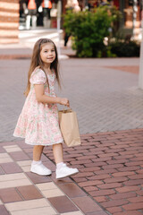 Back view of cute little girl on shopping. Portrait of adorable kid with shopping bags