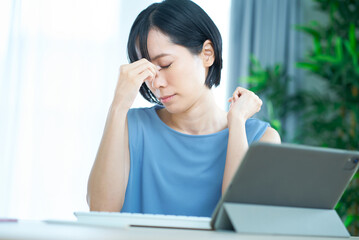 パソコンを前に疲れた表情をする女性