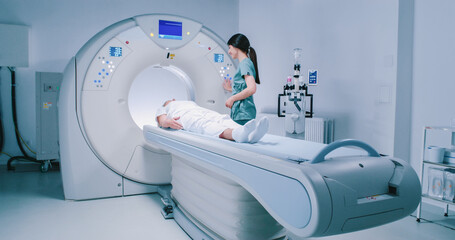 Patient is getting recommendations from doctor before MRI procedure. Woman is lying down at CT scanner bed. Female is moving into MRI scanner capsule. Female doctor is conducting tomography examining. - obrazy, fototapety, plakaty