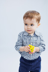 A little boy one year old on a white background with a developing wooden toy. Ecological wooden toys for small children. Child development