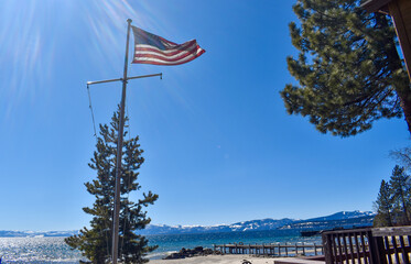 US flag flying on tall flagpole at Lake Tahoe California at cabin resort with sun deck wooden patio furniture 