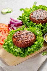 Freshly Grilled Burger Patties,Plant Based Meatless Burgers with Fresh Vegetables on a Wooden Board on Bright Background