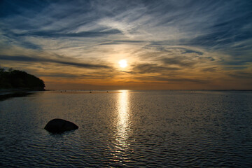 Fototapeta na wymiar Sunset, small rocks in the water at the shore. Light waves. At the Baltic Sea