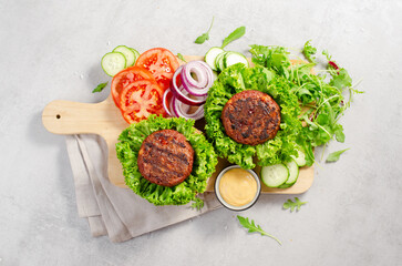 Freshly Grilled Burger Patties,Plant Based Meatless Burgers with Fresh Vegetables on a Wooden Board on Bright Background