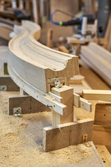 Bending wooden staircase handrail made of oak planks and plywood on table closeup. Detail of stairs fence in carpentry workshop