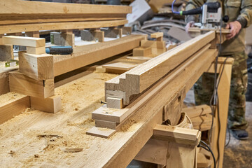 Carpenter milling wooden handrail with router manual milling machine in workshop close up. Handyman processes timber piece with electric instrument © timltv
