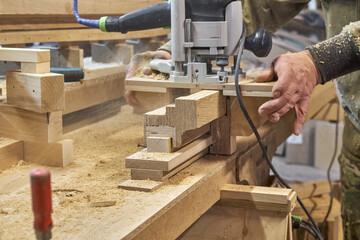 Carpenter milling wooden handrail with router manual milling machine in workshop close up. Handyman...