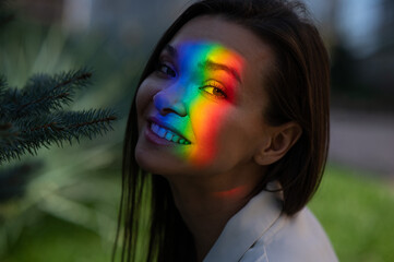 Portrait of caucasian woman with rainbow beam on her face outdoors.