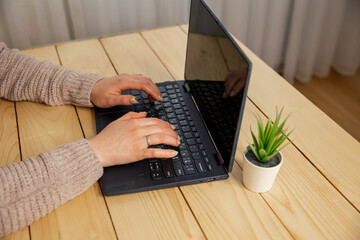 Woman typing on laptop keyboard. Business woman working at laptop, no face. Hands of a female freelancer, working behind the table at home. Young woman working on laptop at home. Girl studying