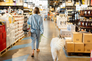 Woman walks with her huge dog in a supermarket. Concept of modern lifestyle and pet-friendly shops