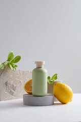 Pastel cosmetic bottle without label standing on gray podium with a half of lemon. Lemon (Citrus...