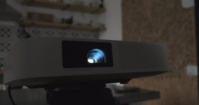 Video operation of an LED home movie projector in dark apartment, close-up.