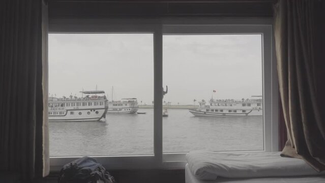 Shot from inside a sleep boat in Vietnam near Halong Bay on a cloudy day with other boats seen through the window LOG