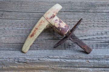 detail from one small old door handle made of gray plastic and brown rusty iron lies on a wooden table