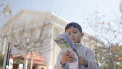 Cute asian boy concentrated on a paper map on a tourist place