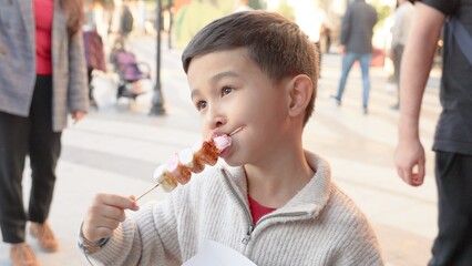 A child bites caramelised marshmallow on a fair