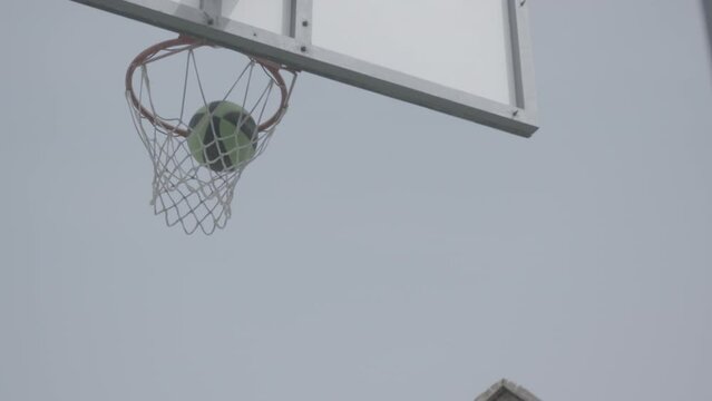 Basketball bouncing on the basket ring and then falling into the goal scoring a point in slowmotion LOG