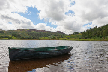 Fototapeta na wymiar Rowing boat on Watendlath Tarn, Lake District, Cumbria, UK. The tarn sits high between the Borrowdale and Thirlmere valleys, surrounded by fells.