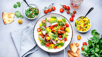 Fresh salad with grilled chicken and mango, salsa, tomatoes, cilantro, red onion and lettuce in tex-mex style, white table background, top view - obrazy, fototapety, plakaty